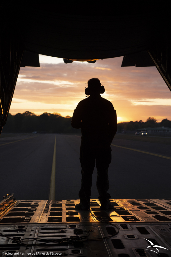 Un mécanicien navigant voit le soleil se coucher derrière l'aéronef.