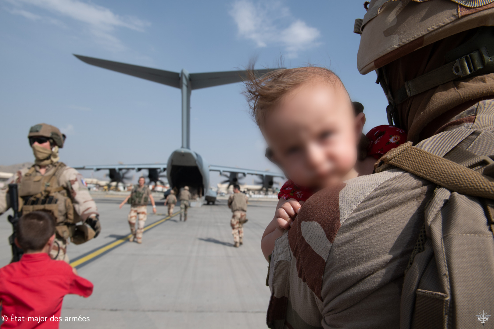 Un enfant Afghan dans les bras d'un militaire français se dirigeant vers un A400M 