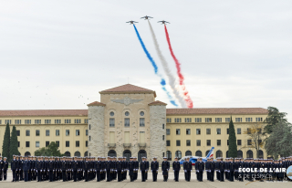 défilé de la patrouille de France qui traîne les trois couleurs du drapeau dans le ciel au-dessus des bâtiments et des élèves officiers en rang
