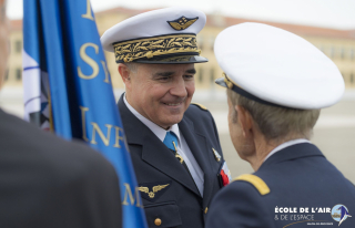 Le général de corps aérien Manuel Alvarez en face d'un élève officier, souriant, près du drapeau