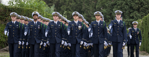 Les élèves-officiers défilent au pas, en bel uniforme de costume.