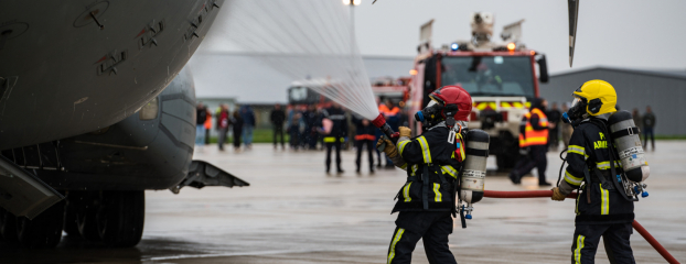 Deux pompiers arrosent l'avion qui simule un accident sur le tarmac