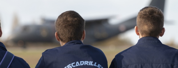 Trois équipiers des escadrilles Air Jeunesse devant un avion de l'armée de l'Air et de l'Espace