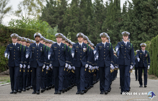Les élèves-officiers défilent au pas, en bel uniforme de costume.
