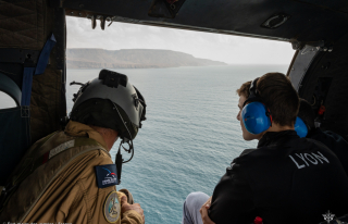 Un Aviateur et un jeune lauréat du BIA en vol basse altitude, porte du PUMA ouverte au-dessus de la mer