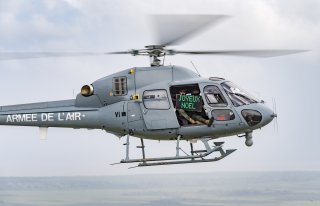 Hélicoptère Fennec en vol avec un militaire tenant un panneau avec l'inscription "Joyeux Noël". 
